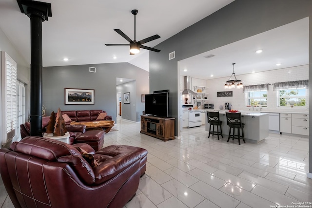 living area featuring lofted ceiling, a wood stove, visible vents, and ceiling fan