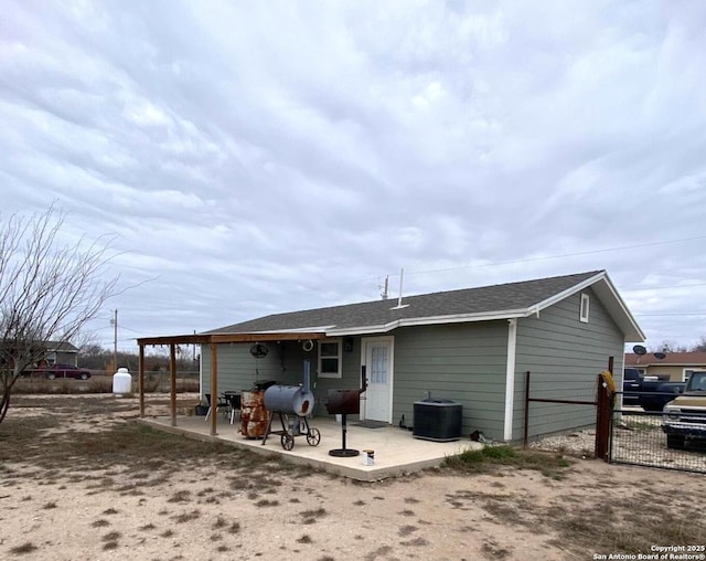 back of house featuring central AC unit, a patio area, fence, and a shingled roof