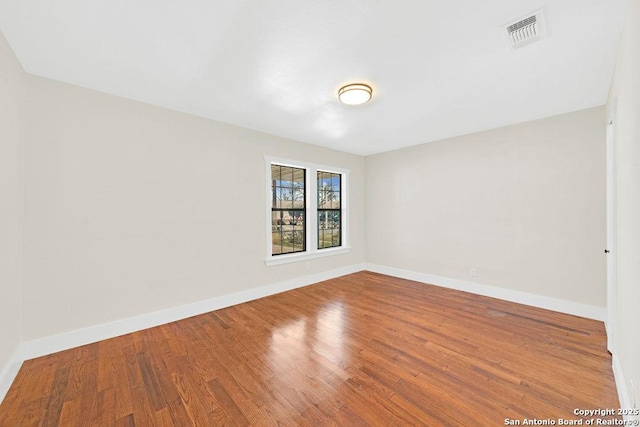 unfurnished room with visible vents, baseboards, and wood finished floors