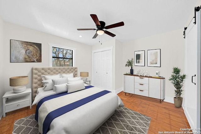 bedroom with a closet, wood finished floors, baseboards, and a barn door