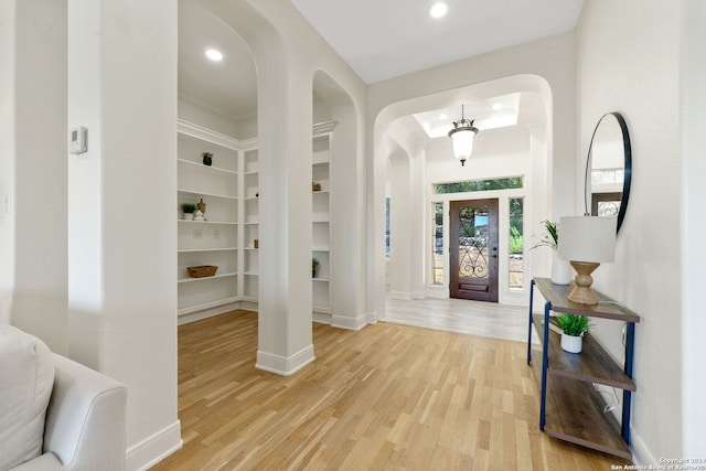 foyer with light wood-type flooring, baseboards, arched walkways, and recessed lighting