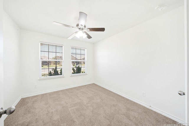 carpeted spare room with a ceiling fan and baseboards