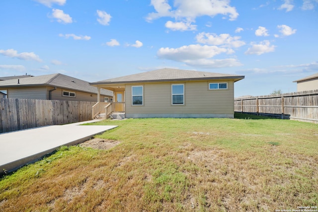 back of property with a fenced backyard, a yard, and a patio