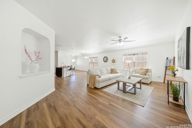 living area featuring wood finished floors, a ceiling fan, and baseboards