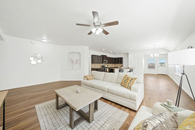 living room featuring baseboards, ceiling fan with notable chandelier, and light wood-style floors