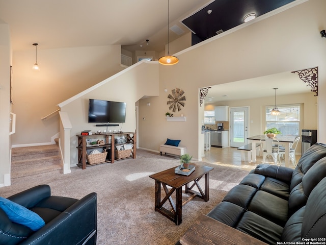 living area with a towering ceiling, stairs, baseboards, and light carpet