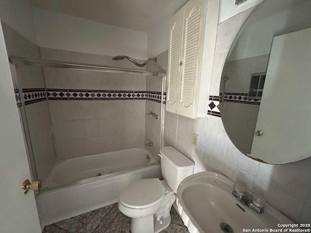 bathroom featuring a sink, tile walls, toilet, and shower / bathing tub combination