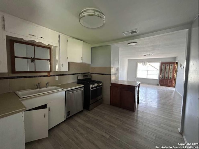 kitchen featuring visible vents, white cabinets, appliances with stainless steel finishes, wood finished floors, and a sink