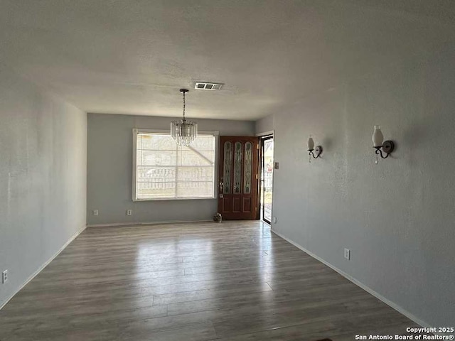 unfurnished dining area featuring dark wood-style flooring, visible vents, and an inviting chandelier