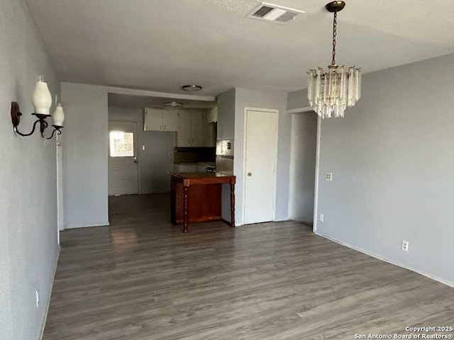 kitchen with visible vents, dark wood finished floors, dark countertops, open floor plan, and a chandelier