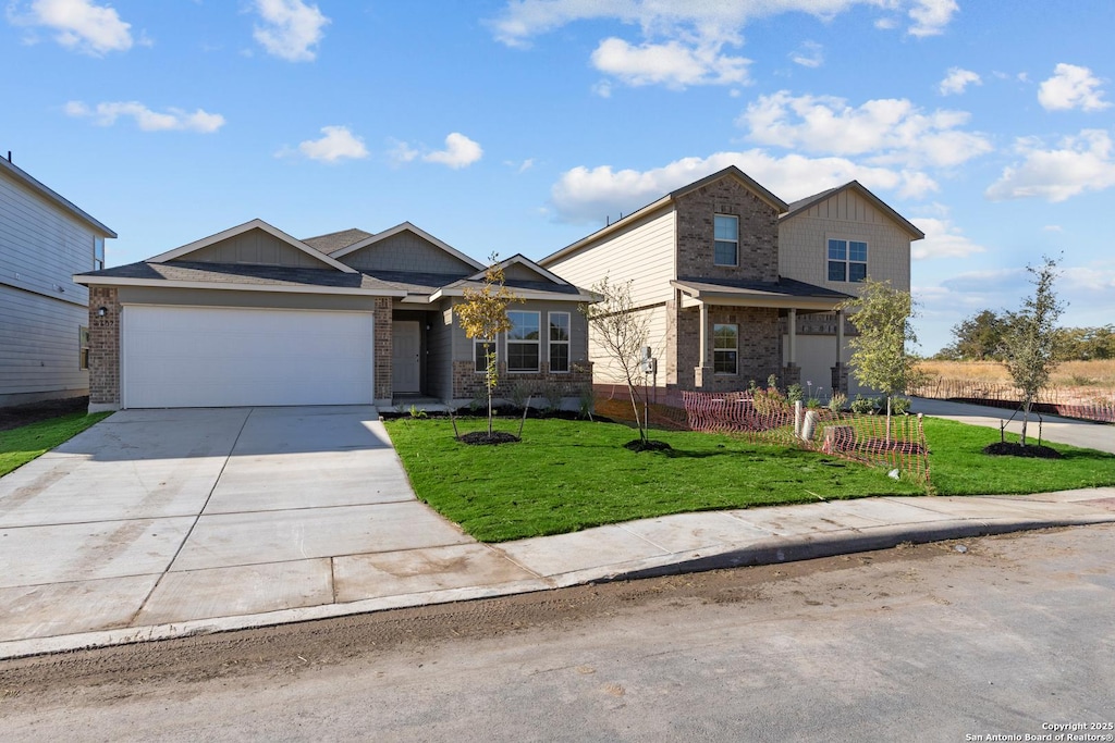 view of front facade featuring a garage, a front yard, brick siding, and driveway