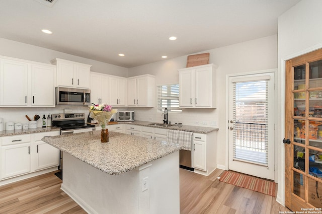 kitchen featuring a sink, white cabinetry, appliances with stainless steel finishes, light wood-type flooring, and tasteful backsplash