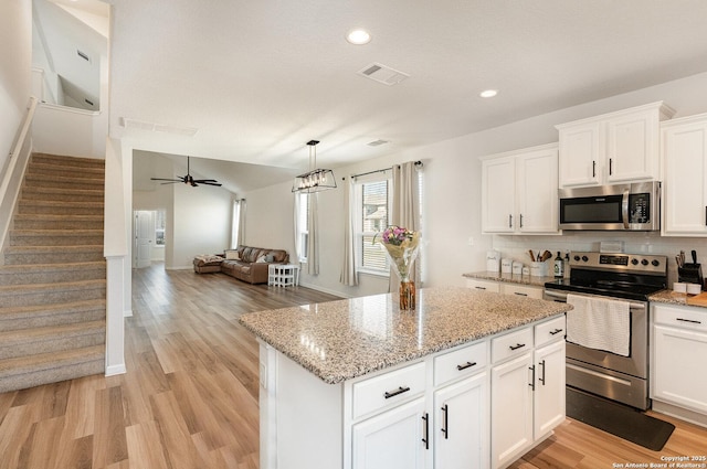 kitchen featuring appliances with stainless steel finishes, open floor plan, light wood-type flooring, white cabinetry, and backsplash