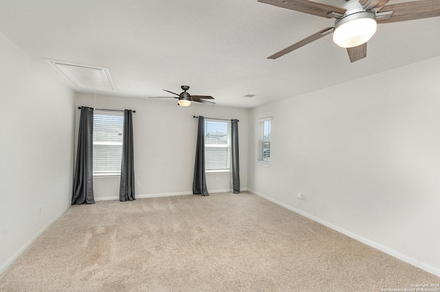 empty room featuring light carpet, attic access, baseboards, and a ceiling fan