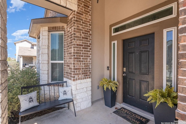 doorway to property featuring covered porch and brick siding