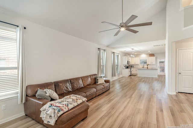 living area with light wood finished floors, a ceiling fan, and a healthy amount of sunlight