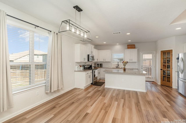 kitchen featuring light wood-type flooring, white cabinetry, visible vents, and stainless steel appliances