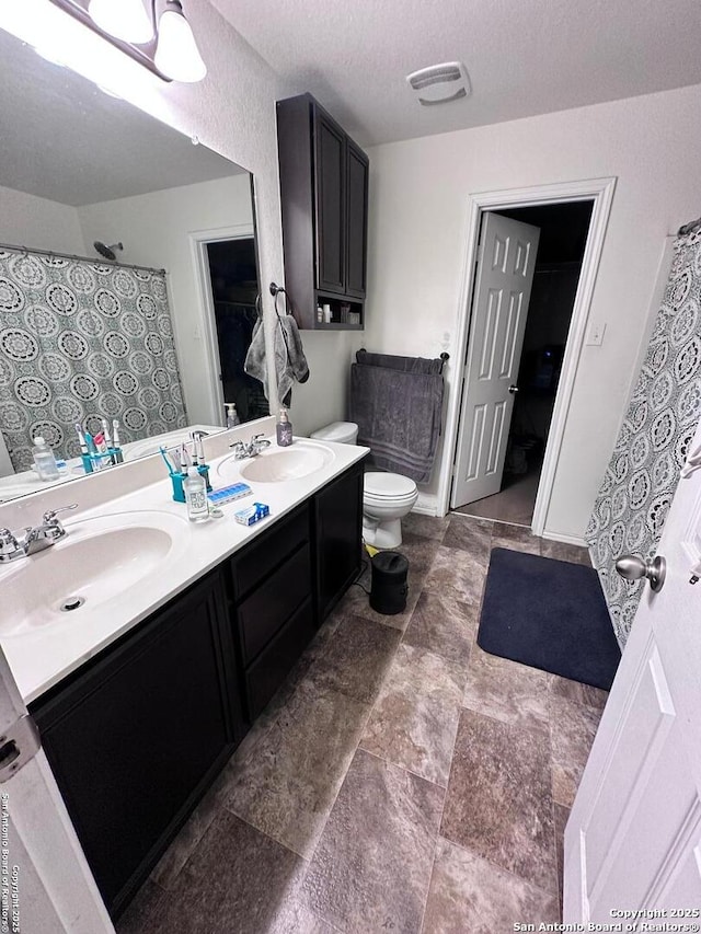 full bath featuring visible vents, double vanity, a sink, and toilet