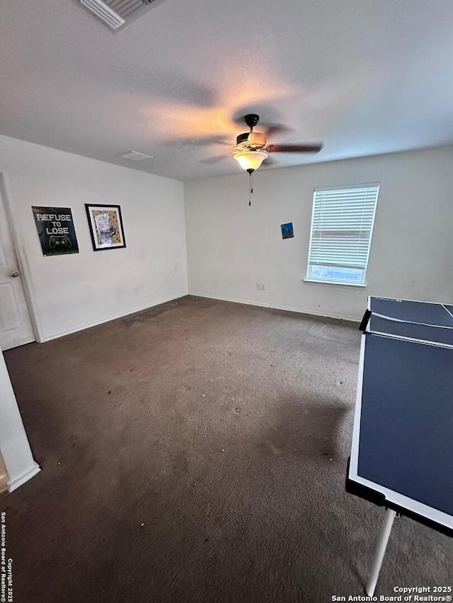 empty room featuring carpet floors, visible vents, and a ceiling fan