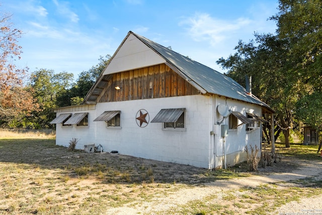 view of property exterior with concrete block siding and metal roof