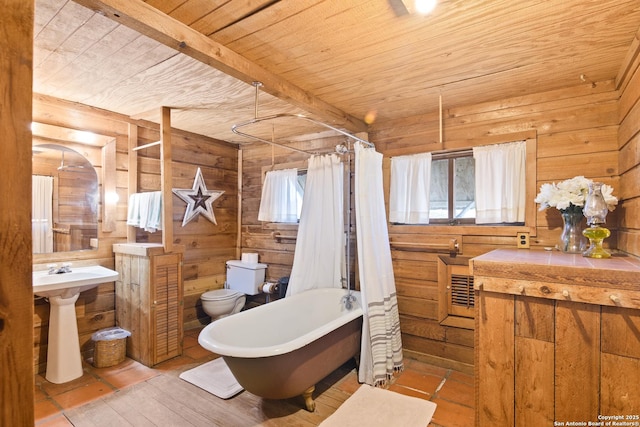 full bath with wooden ceiling, a freestanding tub, and wooden walls