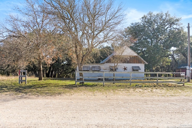 view of front of house with fence and an outbuilding