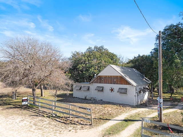 exterior space featuring dirt driveway, concrete block siding, fence, and a garage