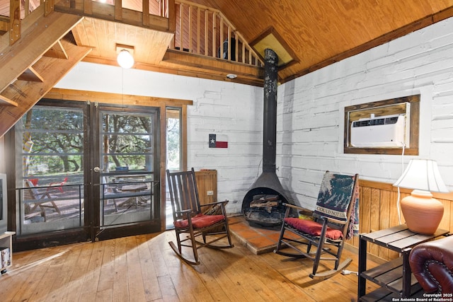 sitting room with lofted ceiling, a wood stove, light wood-type flooring, and wood ceiling