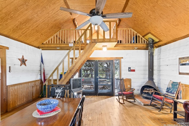 dining area with a wood stove, ceiling fan, high vaulted ceiling, wooden ceiling, and hardwood / wood-style floors