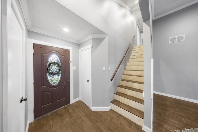 foyer entrance featuring baseboards, wood finished floors, visible vents, and crown molding