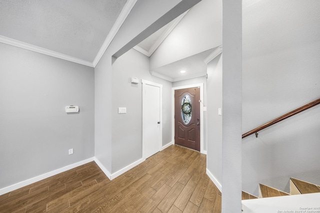 entryway featuring baseboards, lofted ceiling, stairway, wood finished floors, and crown molding