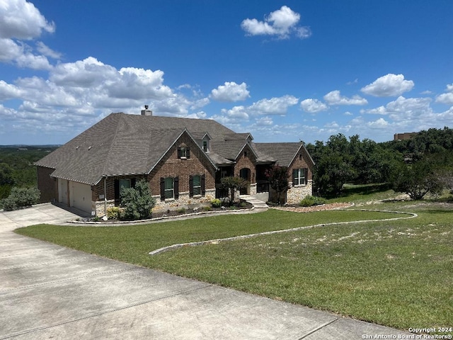 view of front of home featuring driveway, a chimney, an attached garage, a front yard, and brick siding