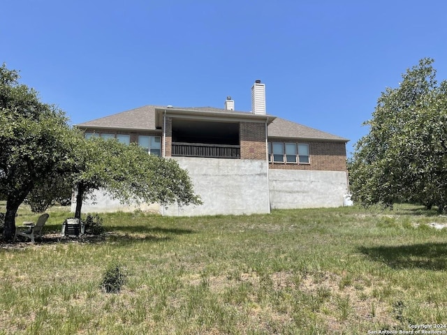 view of side of property featuring brick siding, a yard, and a chimney