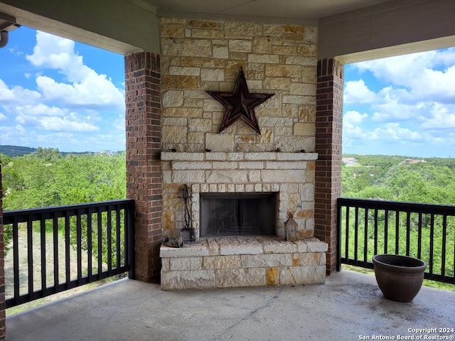 view of patio / terrace featuring an outdoor stone fireplace and a view of trees