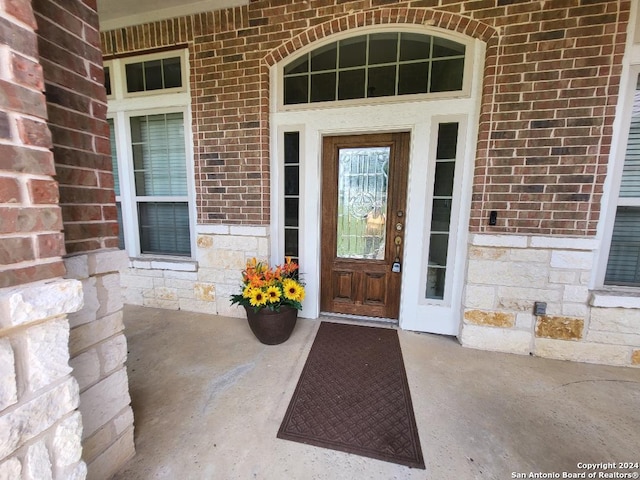 entrance to property featuring stone siding, brick siding, and a porch
