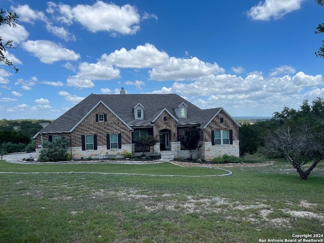 view of front of property featuring stone siding, a chimney, a front lawn, and brick siding