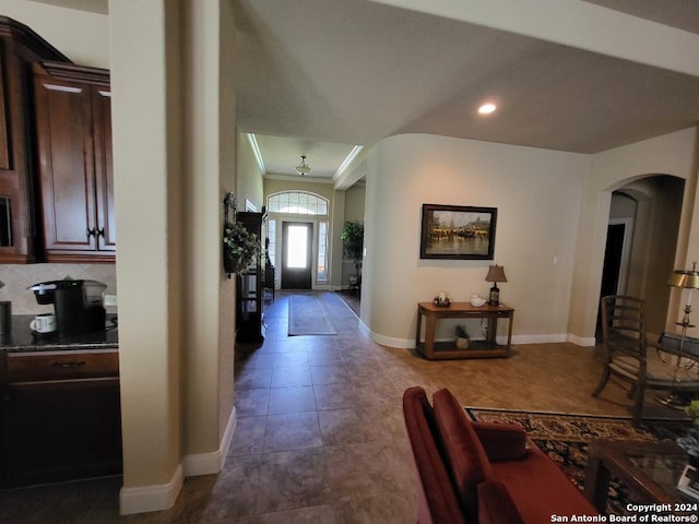 tiled entryway with arched walkways, crown molding, recessed lighting, and baseboards
