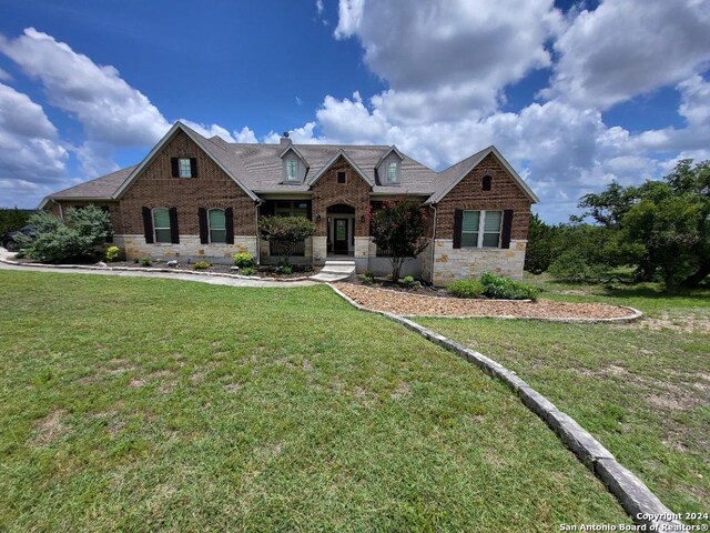 view of front of property featuring a front yard, stone siding, and brick siding