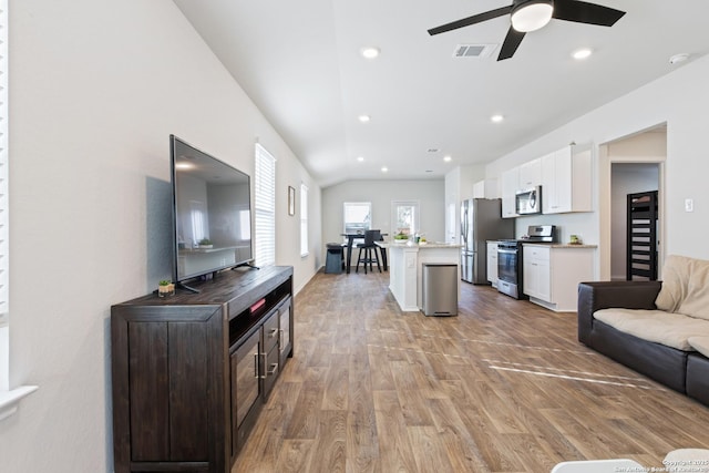 living area with recessed lighting, a ceiling fan, visible vents, vaulted ceiling, and light wood finished floors