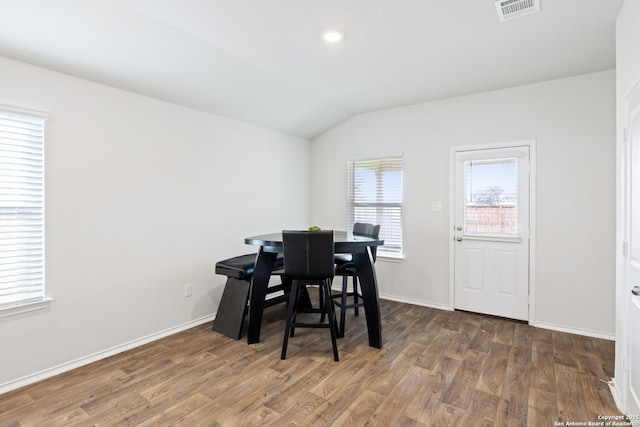 dining room featuring lofted ceiling, wood finished floors, visible vents, and baseboards