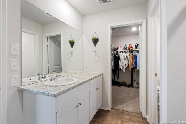 bathroom featuring a spacious closet, visible vents, wood finished floors, and vanity