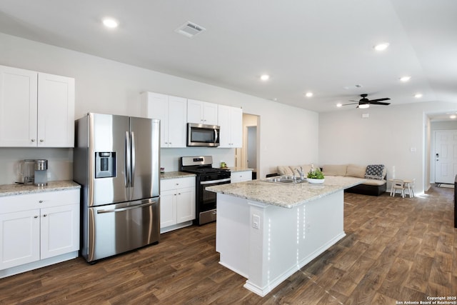 kitchen with dark wood-style floors, stainless steel appliances, visible vents, white cabinets, and a sink