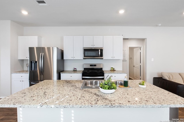 kitchen with visible vents, white cabinets, appliances with stainless steel finishes, a center island, and a sink