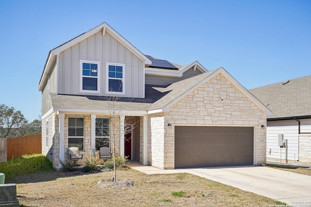 view of front of home with a garage, solar panels, concrete driveway, stone siding, and board and batten siding