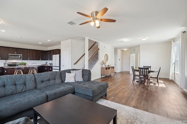 living room with recessed lighting, visible vents, baseboards, stairway, and dark wood finished floors