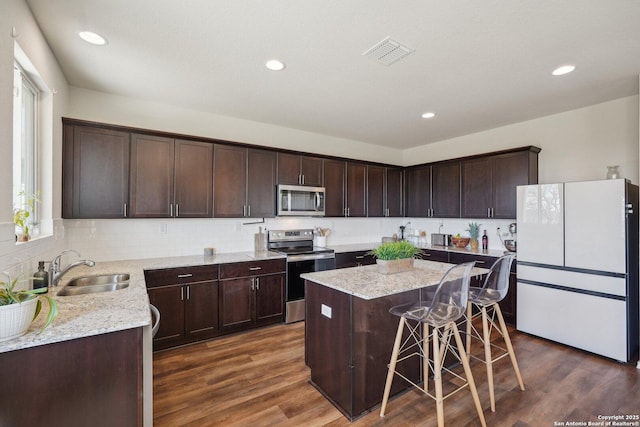 kitchen featuring dark wood-type flooring, visible vents, stainless steel appliances, and a sink