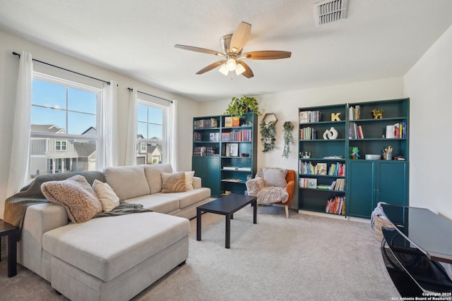 sitting room featuring ceiling fan, visible vents, a textured ceiling, and light colored carpet