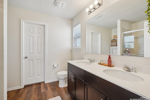 full bathroom with a stall shower, a sink, toilet, and wood finished floors