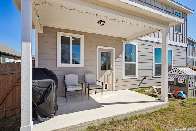 exterior space featuring board and batten siding, a patio, and fence