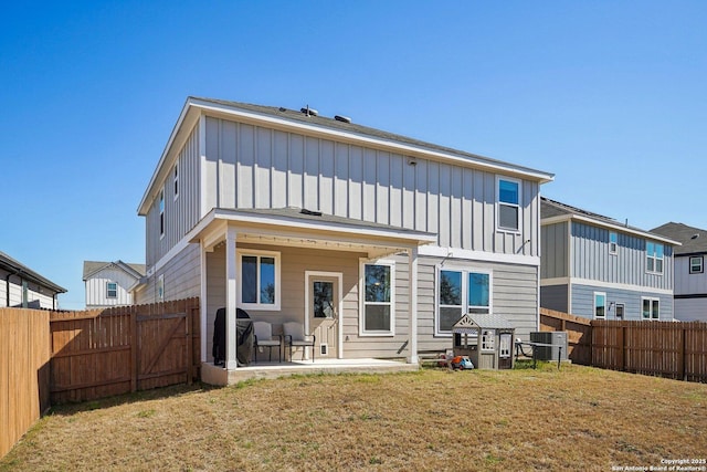 rear view of house featuring a fenced backyard, central air condition unit, a lawn, board and batten siding, and a patio area